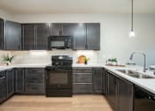 Thumbnail 1 of 18 - A kitchen with black cabinets and a black oven.