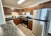 Thumbnail 15 of 27 - A kitchen with a stainless steel refrigerator and wooden cabinets.