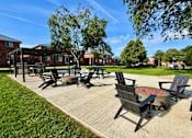Thumbnail 1 of 27 - A sunny day at a park with a fire pit and chairs.