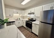 Thumbnail 16 of 27 - A kitchen with white cabinets and stainless steel appliances.
