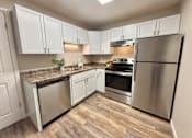 Thumbnail 12 of 27 - A kitchen with white cabinets and stainless steel appliances.