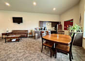 Thumbnail 5 of 34 - A living room with a brown couch, a wooden table, and a television mounted on the wall.