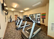 Thumbnail 8 of 34 - A gym with treadmills and a television mounted on the wall.