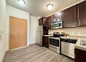 Thumbnail 21 of 34 - A kitchen with a refrigerator, oven, microwave, and sink.