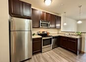 Thumbnail 25 of 34 - A modern kitchen with dark brown cabinets and stainless steel appliances.