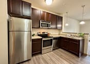 Thumbnail 28 of 34 - A kitchen with a stainless steel refrigerator, microwave, oven, and sink.