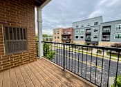 Thumbnail 34 of 34 - A balcony with a black railing and a brick wall.