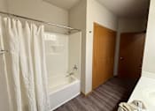 Thumbnail 30 of 34 - A bathroom with a white tub and a shower curtain.