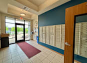 Thumbnail 11 of 34 - A hallway with a red carpet and a wall of mailboxes.