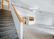 Thumbnail 32 of 60 - a living room with a staircase and a white wall