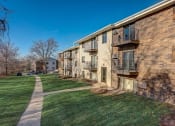 Thumbnail 46 of 47 - a brick apartment building with green grass and a sidewalk