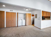Thumbnail 39 of 60 - an empty living room with a kitchen with a refrigerator and a sink