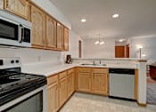 Thumbnail 19 of 44 - A kitchen with wooden cabinets and black appliances.