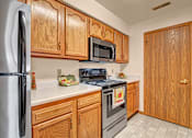 Thumbnail 24 of 44 - A kitchen with wooden cabinets and a stainless steel refrigerator.