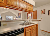 Thumbnail 23 of 44 - A kitchen with wooden cabinets and a stainless steel sink.