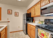 Thumbnail 21 of 44 - A kitchen with wooden cabinets and a black refrigerator.