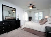 Thumbnail 37 of 44 - A bedroom with a large bed, a dresser, and a ceiling fan.