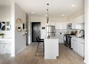 Thumbnail 6 of 21 - A modern kitchen with white cabinets and a black door.