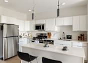 Thumbnail 3 of 21 - A modern kitchen with white cabinets and a stainless steel refrigerator.