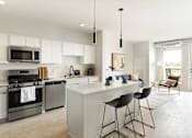 Thumbnail 5 of 21 - A modern kitchen with a white island and bar stools.