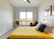 Thumbnail 10 of 21 - A bedroom with a yellow bed and a window overlooking the grass.