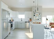 Thumbnail 12 of 21 - A modern kitchen with white cabinets and a large island.