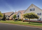 Thumbnail 10 of 10 - A white house with a brown roof and a tree in front of it.