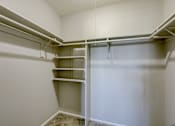Thumbnail 25 of 31 - A white closet with shelves and a carpeted floor.