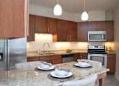 Thumbnail 28 of 31 - A kitchen with a granite countertop and a stainless steel refrigerator.