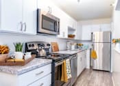 Thumbnail 37 of 43 - A modern kitchen with white cabinets and stainless steel appliances.