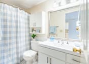 Thumbnail 43 of 43 - A bathroom with a white toilet, sink, and shower curtain.