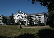 Thumbnail 6 of 44 - A large house with a white and grey exterior and a dark roof.