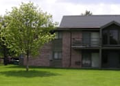 Thumbnail 20 of 21 - a brick house with a tree in the grass