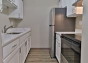 Thumbnail 1 of 21 - an empty kitchen with white cabinets and stainless steel appliances