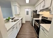 Thumbnail 1 of 10 - A kitchen with white cabinets and a black fridge.