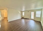 Thumbnail 4 of 10 - A room with wooden flooring and white walls.