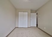 Thumbnail 7 of 21 - a living room with white walls and a carpet and two closets