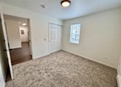 Thumbnail 5 of 10 - A room with a carpeted floor and a door leading to another room.