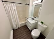 Thumbnail 6 of 10 - A white bathroom with a toilet, sink, and shower.