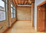 Thumbnail 28 of 35 - an empty room with brick wall and wooden floors and a wooden door
