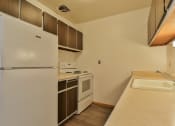Thumbnail 17 of 33 - A white refrigerator is in a kitchen with a sink and stove.