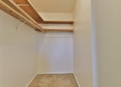 Thumbnail 28 of 33 - A huge closet with a carpeted floor and wooden beams on the ceiling.