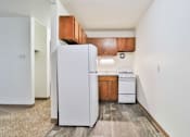 Thumbnail 2 of 11 - A white refrigerator is in a kitchen with wood cabinets.