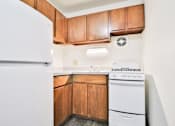 Thumbnail 1 of 11 - A white refrigerator is in a kitchen with wooden cabinets.