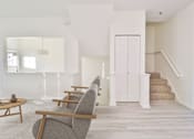 Thumbnail 8 of 102 - A living room with a grey chair and a staircase.