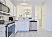 Thumbnail 3 of 102 - A modern kitchen with white cabinets and a black stove top oven.