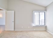 Thumbnail 46 of 47 - A room with a carpeted floor, a window with blinds, and a door.
