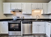 Thumbnail 24 of 39 - A modern kitchen with white cabinets and black countertops.