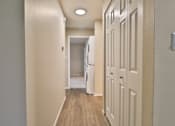 Thumbnail 32 of 39 - A hallway with a white door on the right and a white fridge in the middle.