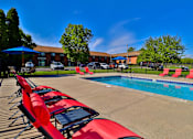 Thumbnail 3 of 33 - A poolside with red sun loungers and a blue umbrella.